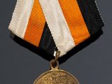 an image of a medal with an orange, white, and black ribbon around it