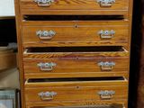 a tall wooden chest of drawers sitting on a tile floor