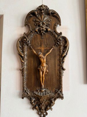 un crucifix en bois accroché au mur d'une pièce où se trouvent des photos encadrées