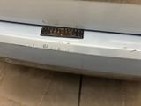 the bumper of a white car with a sticker on it ' s bumper