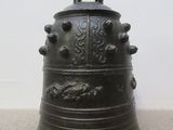 a large metal bell sitting on the floor next to a white wall