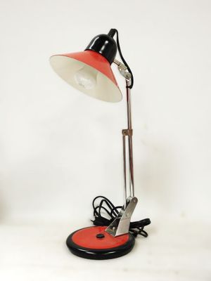 une photo d'une lampe de bureau rouge et noire posée sur une surface blanche