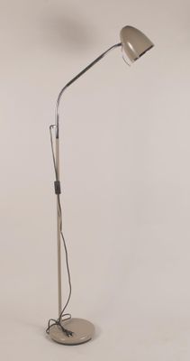 Le lampadaire est doté d'un pied en métal et d'une base blanche.