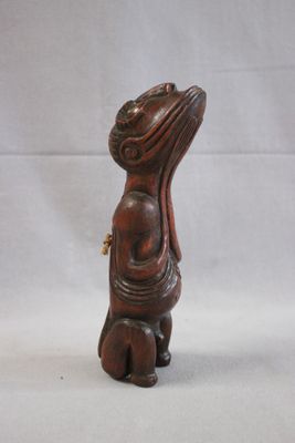 wooden statue of a woman with a hat on her head sitting on a stool