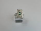 a close up of a ring with a green stone surrounded by white diamonds
