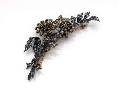 une image représentant une broche en forme de fleur noire et dorée sur fond blanc