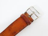 someone is holding a brown leather belt with a metal buckle