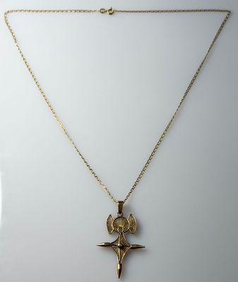 a gold necklace with a cross and a bird on it