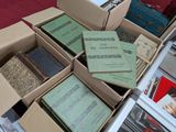 Plusieurs cartons remplis de livres sont empilés sur une table recouverte d'une nappe rouge.