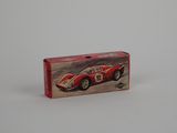 a small red toy car in a box on a white surface