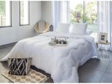 a bed with a white comforter and pillows in a room