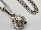 a close up of a silver necklace with a diamond in the center