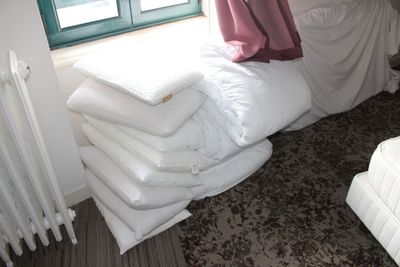 une pile d'oreillers posée sur un lit, à côté d'un radiateur
