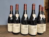 six bottles of wine are lined up on a wooden table