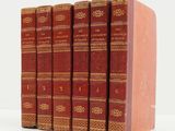 six livres rouges alignés sur une surface blanche