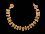a close up of a gold necklace on a black background