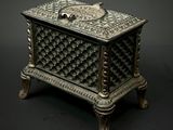 an ornate silver box with a lid on a black background