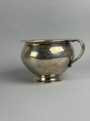 an antique silver plated sugar bowl with a handle on a white surface