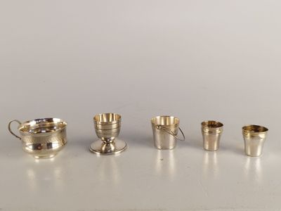 Plusieurs coupes et tasses en argent sont alignées sur une table