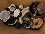 a cardboard box filled with many different types of cups and saucers