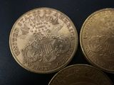 three gold coins sitting on top of each other on a black surface