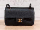 a black chanel bag sitting on top of a wooden table