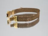 gold plated metal bracelet with two metal clasps on a white surface