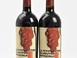 two bottles of red wine sitting next to each other on a white surface