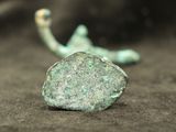 a small rock sitting on the ground next to a hook