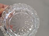 a person holding a clear glass bowl on a table