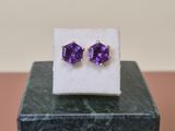 une paire de boucles d'oreilles en améthorate posées sur un bloc de marbre