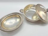 two silver plated dishes with lids on a white surface