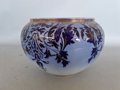 a blue and white vase with a gold rim on a table