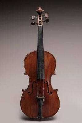 an old violin sitting on top of a table next to a wall