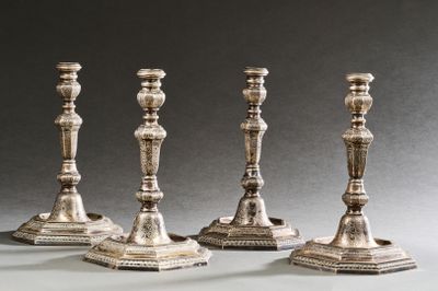 quatre bougeoirs en argent sont alignés sur une table