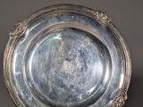 an antique silver plate on a stand on a gray background