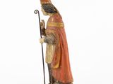 an old statue of a man in a red robe holding a staff
