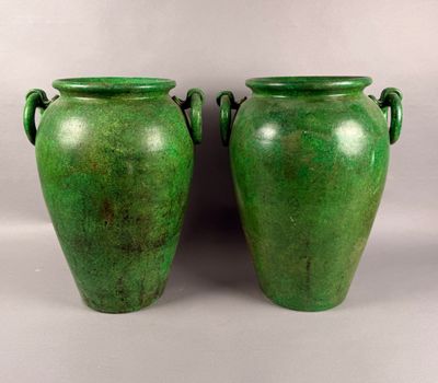 une paire de vases verts munis d'anses, posés sur une surface blanche