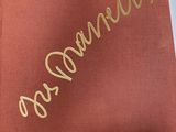 an open book with gold lettering on it sitting on top of a table