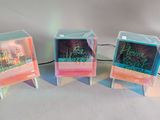 three clear cubes with neon lights on top of a white surface