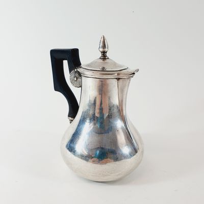 a silver coffee pot with a black handle on a white surface