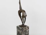 une sculpture en bronze représentant une femme posée sur un bloc de marbre