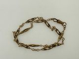 a close up of a bracelet with a chain on a white surface