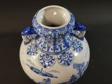 a blue and white vase with a bow on the handle