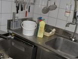 a kitchen with a sink, dishwasher, and other items hanging on the wall