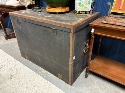 une vieille malle posée à côté d'une table sur laquelle se trouve un vase