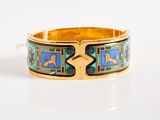 an image of a close up of a gold bracelet with blue and green designs