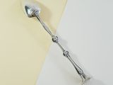 a silver spoon with a handle on a yellow and white surface
