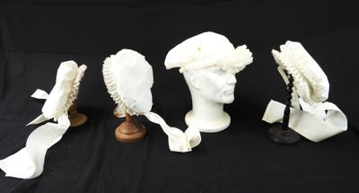 trois têtes de mannequins blanches coiffées de chapeaux, sur fond noir