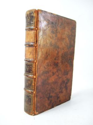 an old book sitting on top of a white table next to a white wall